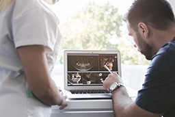 a dentist pointing at a patient’s X-rays