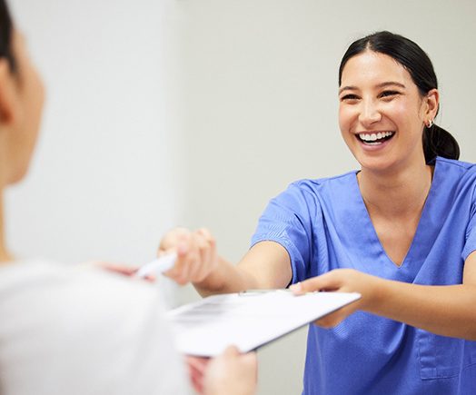 Closeup of woman smiling while holding clear aligner