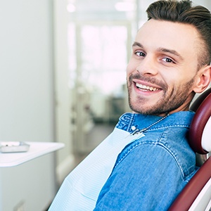 Man in denim jack sitting in dental chair and smiling