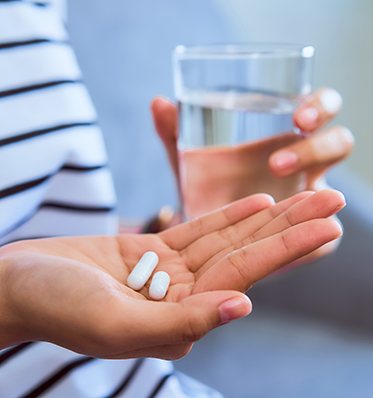 Patient holding pills and a glass of water