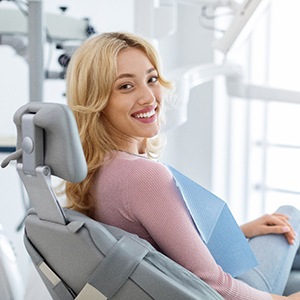 Woman in pink shirt sitting in dental chair and smiling